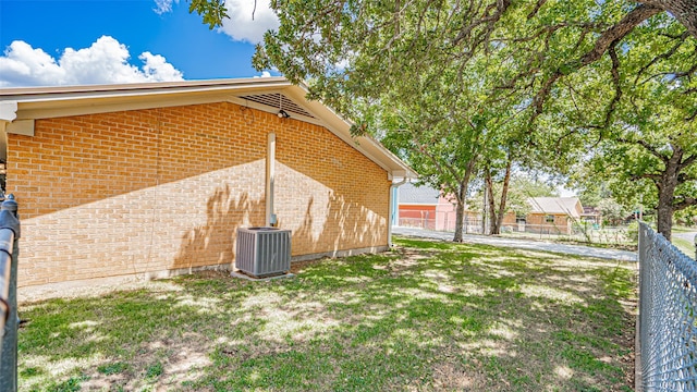 view of side of home featuring central AC and a yard