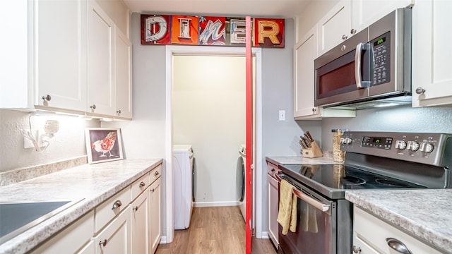 kitchen with light hardwood / wood-style floors, separate washer and dryer, white cabinetry, and appliances with stainless steel finishes