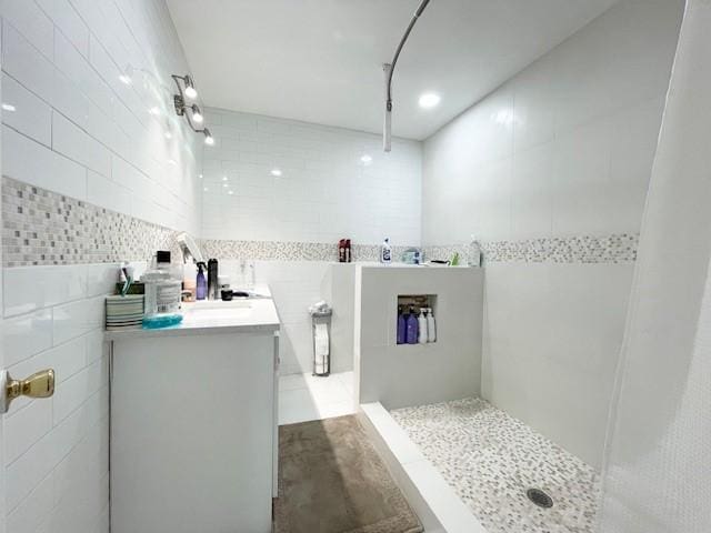 bathroom with a shower, vanity, and tile walls