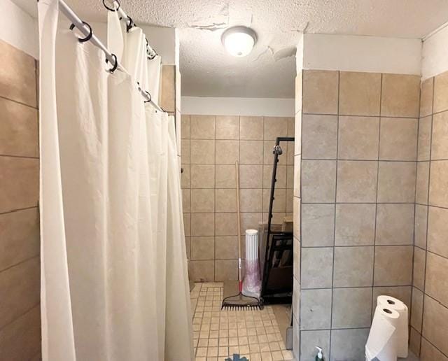 bathroom featuring a textured ceiling, tile walls, and walk in shower