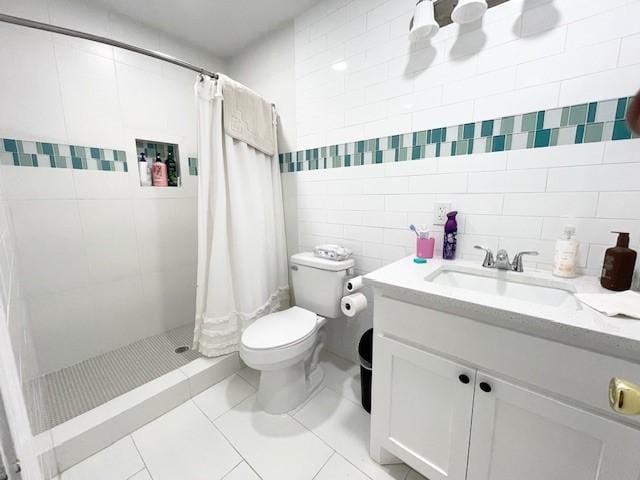 bathroom featuring vanity, tile patterned flooring, toilet, tile walls, and curtained shower