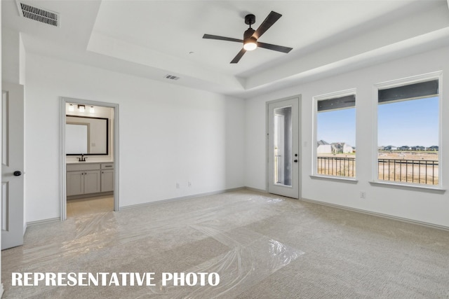 carpeted spare room with ceiling fan and a tray ceiling