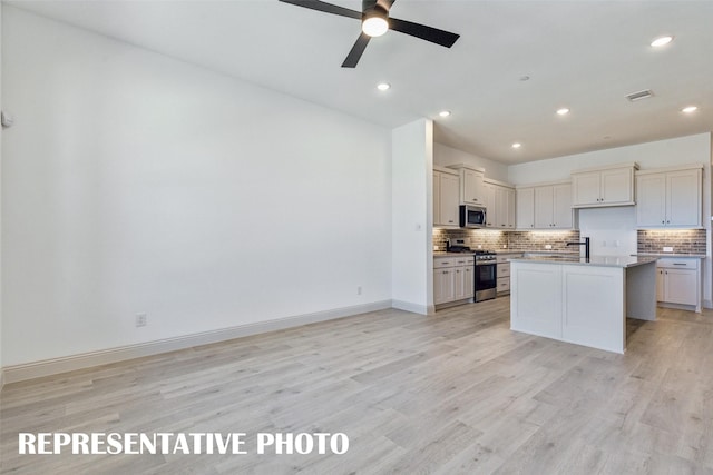 kitchen featuring tasteful backsplash, stainless steel appliances, ceiling fan, a center island, and light hardwood / wood-style floors