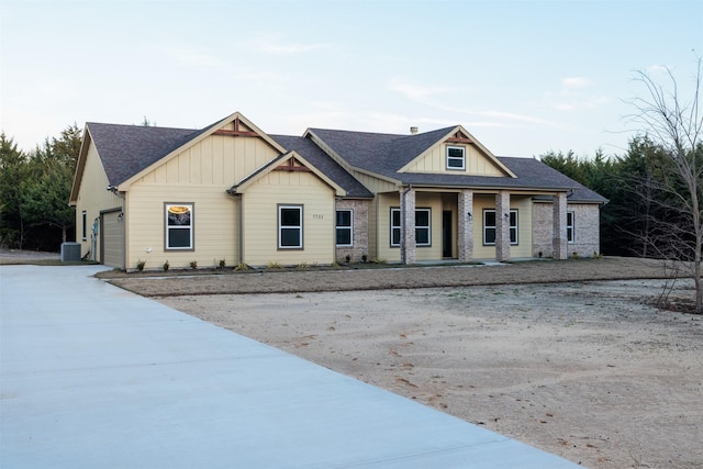 view of front facade with covered porch, a garage, and central air condition unit