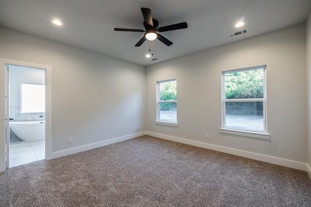 carpeted empty room with ceiling fan and a wealth of natural light