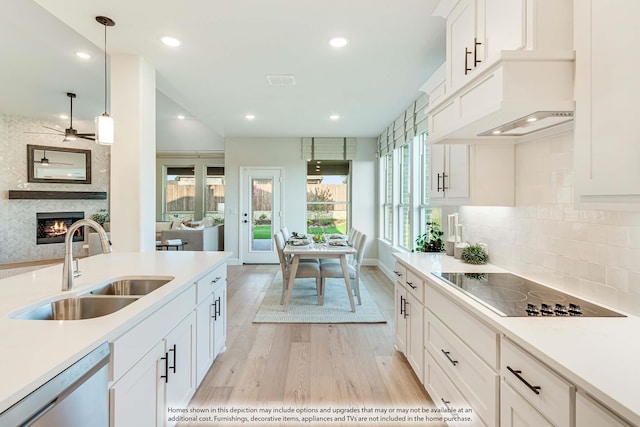 kitchen with pendant lighting, sink, stainless steel dishwasher, black electric cooktop, and white cabinetry