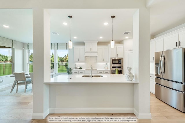 kitchen featuring pendant lighting, white cabinets, sink, light wood-type flooring, and appliances with stainless steel finishes