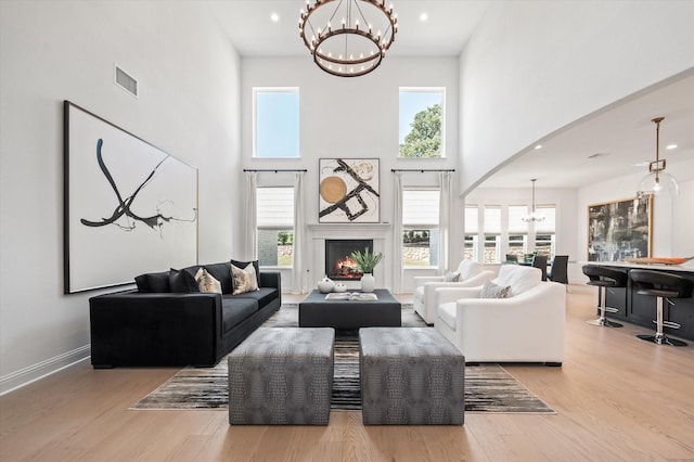 living room with a towering ceiling, light hardwood / wood-style flooring, and a chandelier