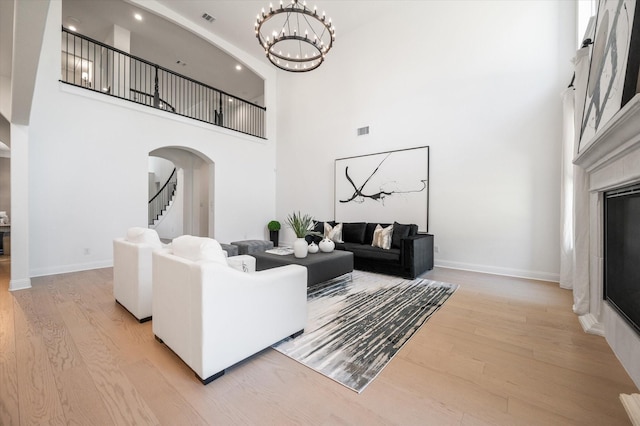 living room featuring a notable chandelier, a high ceiling, and light hardwood / wood-style flooring