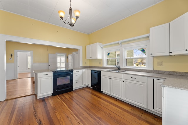 kitchen featuring decorative light fixtures, sink, white cabinets, and black appliances