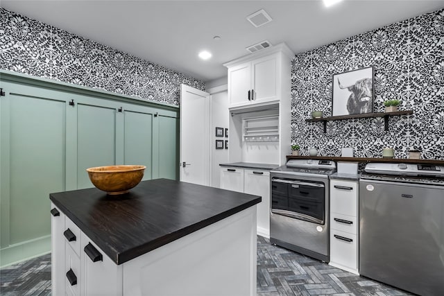 kitchen featuring white cabinets, refrigerator, stainless steel electric range oven, a kitchen island, and washing machine and clothes dryer