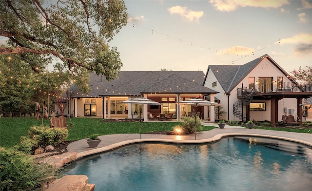 pool at dusk with a lawn and a patio area