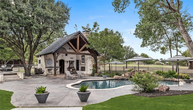 view of swimming pool with a gazebo, an outdoor fireplace, and a patio