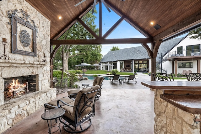 view of patio featuring exterior bar and an outdoor stone fireplace