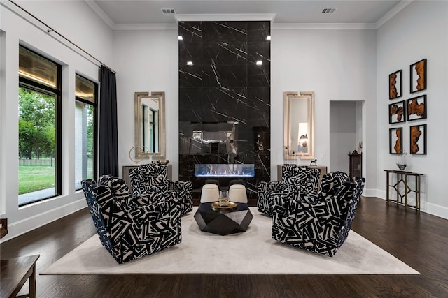 living room featuring plenty of natural light, dark hardwood / wood-style floors, a premium fireplace, and crown molding