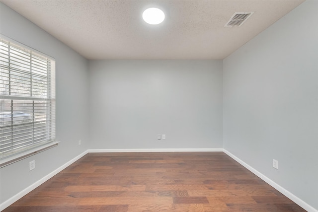 unfurnished room with a textured ceiling and dark wood-type flooring