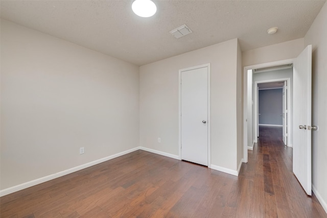 unfurnished bedroom featuring a closet, dark hardwood / wood-style flooring, and a textured ceiling