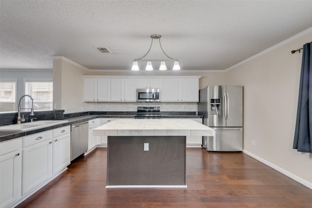 kitchen with sink, white cabinetry, dark hardwood / wood-style flooring, pendant lighting, and appliances with stainless steel finishes