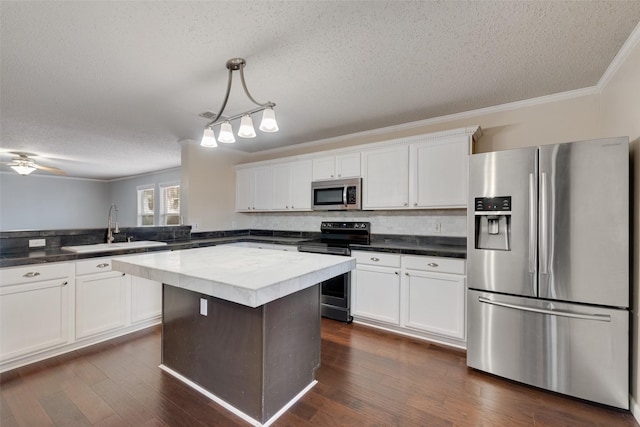 kitchen featuring stainless steel appliances, kitchen peninsula, a textured ceiling, sink, and decorative light fixtures