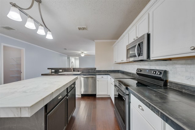 kitchen featuring tasteful backsplash, stainless steel appliances, white cabinets, decorative light fixtures, and sink