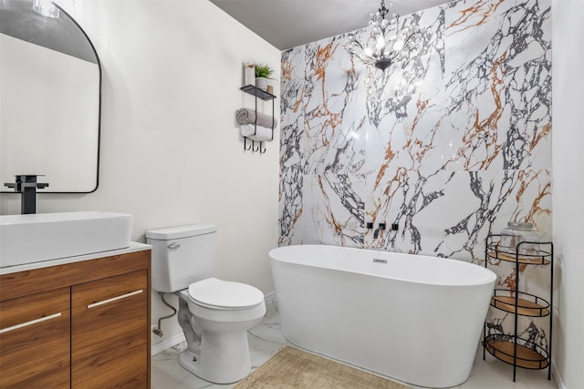 bathroom featuring a notable chandelier, vanity, toilet, and a bath