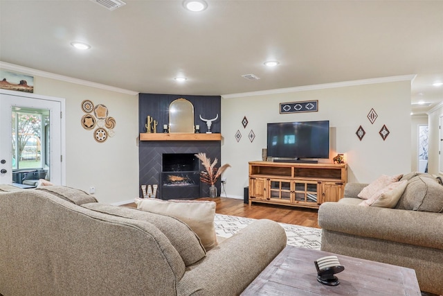 living room featuring hardwood / wood-style floors, a large fireplace, and crown molding