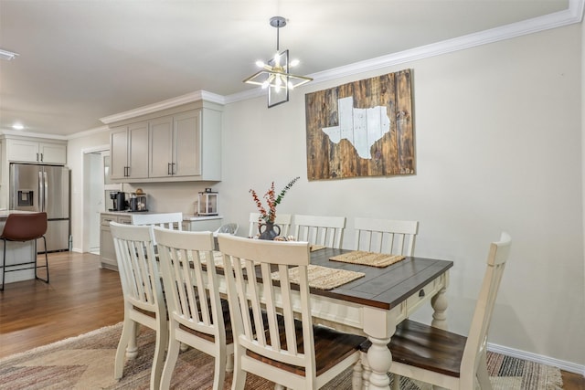 dining space with hardwood / wood-style floors, crown molding, and an inviting chandelier