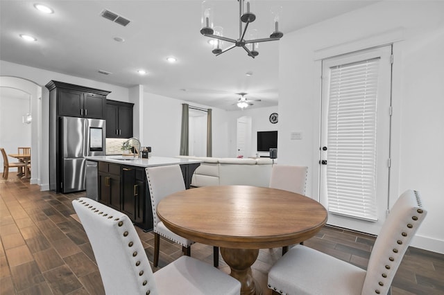 dining area featuring sink and ceiling fan with notable chandelier