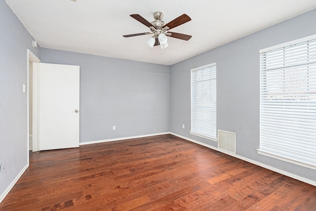 spare room with a textured ceiling, ceiling fan, and dark wood-type flooring