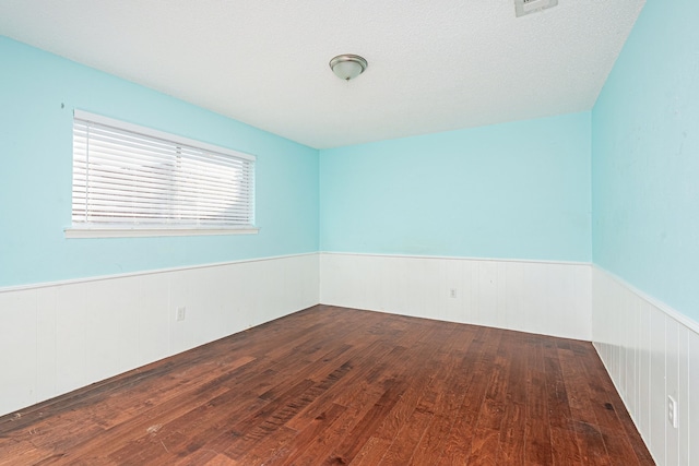 spare room with dark hardwood / wood-style flooring and a textured ceiling