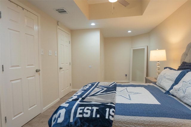 carpeted bedroom featuring a raised ceiling and ceiling fan