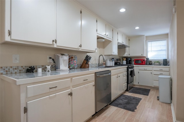 kitchen featuring appliances with stainless steel finishes, light wood-type flooring, white cabinetry, and sink