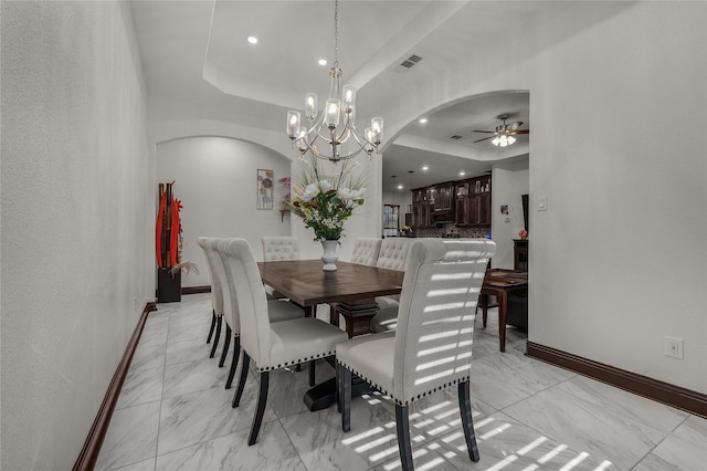 dining room featuring a raised ceiling and ceiling fan with notable chandelier