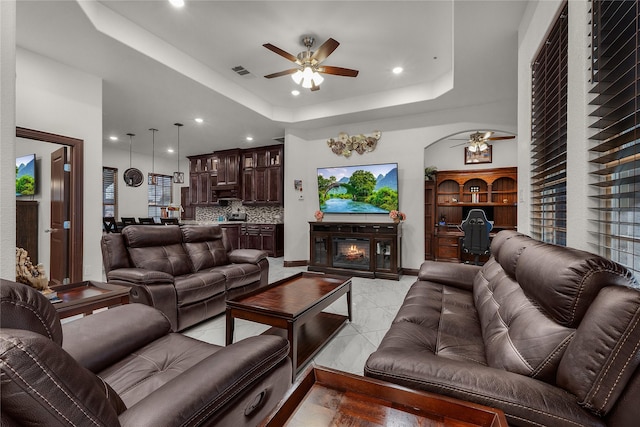 tiled living room featuring a tray ceiling and ceiling fan