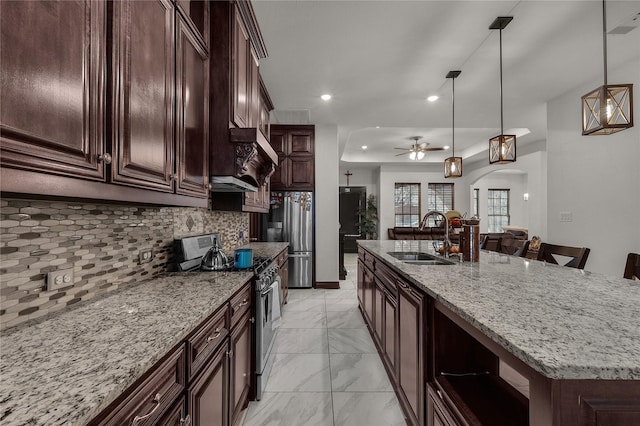 kitchen featuring pendant lighting, a center island with sink, sink, ceiling fan, and appliances with stainless steel finishes