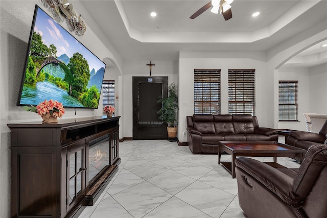 living room featuring a tray ceiling and ceiling fan