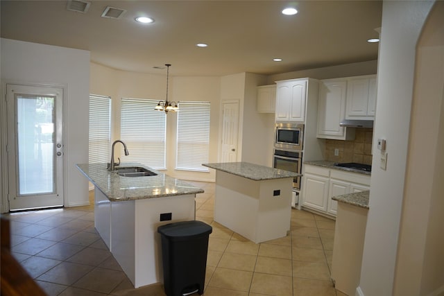 kitchen featuring sink, stainless steel appliances, pendant lighting, a center island with sink, and white cabinets