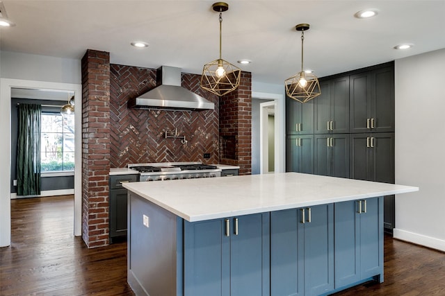 kitchen with dark wood-type flooring, wall chimney exhaust hood, hanging light fixtures, and a kitchen island