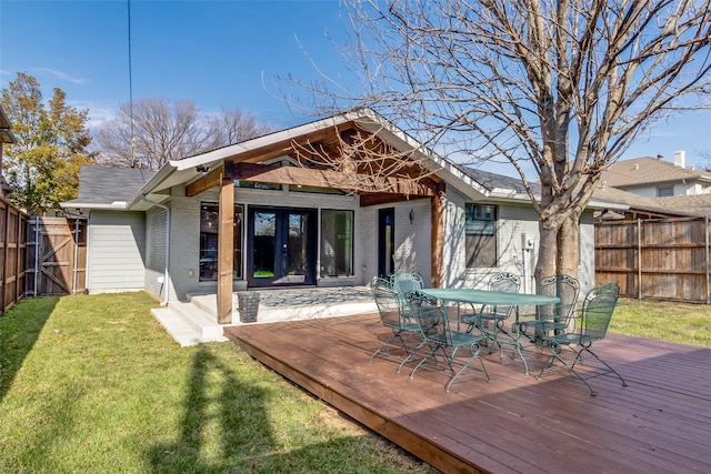 rear view of property with a lawn, a wooden deck, and french doors