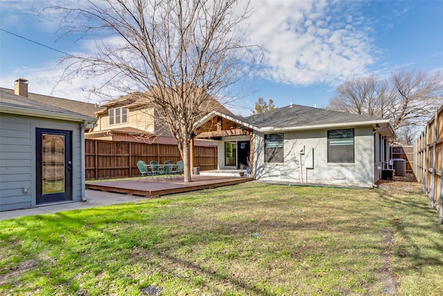 rear view of property with a lawn, a wooden deck, and cooling unit