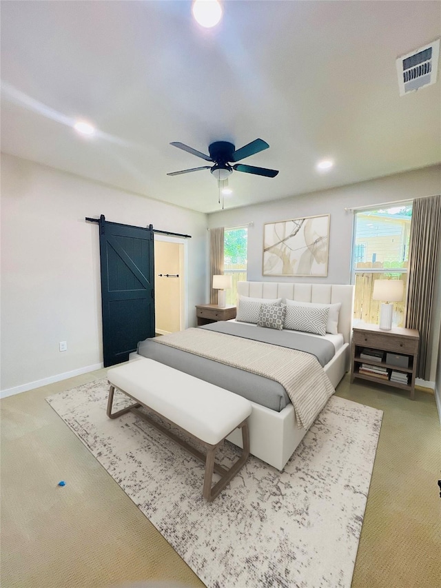 bedroom featuring ceiling fan, a barn door, and carpet floors