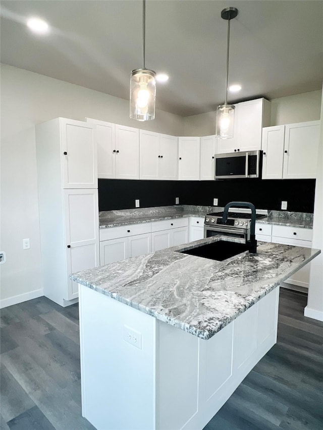 kitchen with white cabinets, pendant lighting, a center island with sink, and appliances with stainless steel finishes