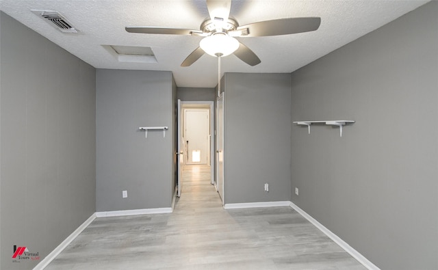 empty room with ceiling fan, light hardwood / wood-style floors, and a textured ceiling