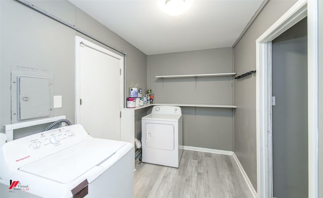 washroom featuring separate washer and dryer, electric panel, and light hardwood / wood-style flooring