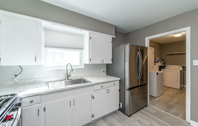 kitchen with tasteful backsplash, stainless steel appliances, sink, washer / clothes dryer, and white cabinetry