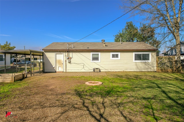 back of property with a yard and an outdoor fire pit