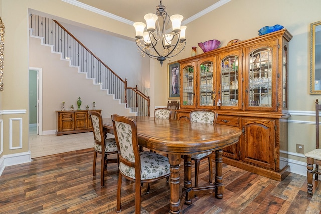 dining space with dark wood-type flooring, ornamental molding, and a chandelier