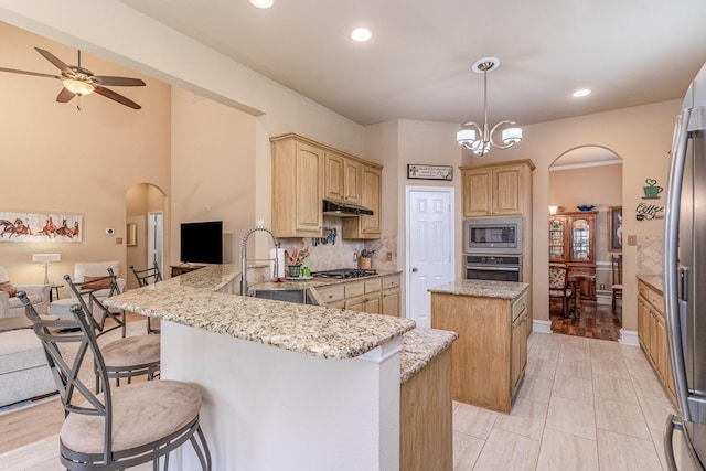 kitchen with sink, a kitchen breakfast bar, kitchen peninsula, pendant lighting, and stainless steel appliances