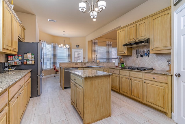 kitchen with sink, a center island, light stone counters, stainless steel appliances, and an inviting chandelier