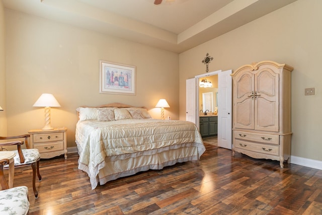 bedroom with dark wood-type flooring, a raised ceiling, and ensuite bathroom